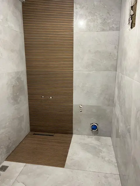 Ahşap görünümlü şerit seramik ve gri büyük ebat seramikle tamamlanan duş alanı