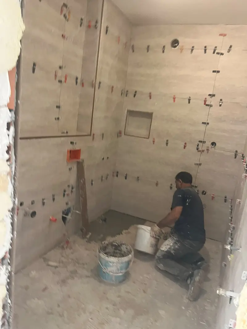 Duruseramix ustası banyo duvarına seramik döşerken, tesviye klipsleriyle