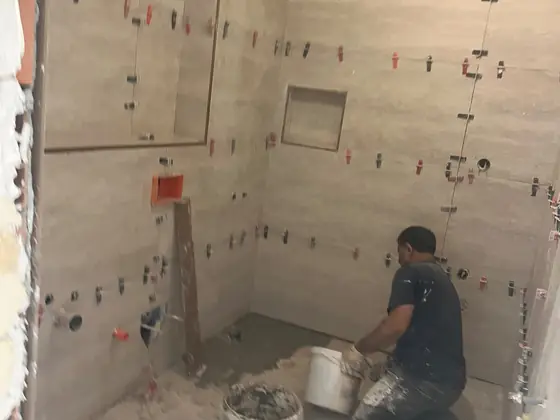 Duruseramix ustası banyo duvarına seramik döşerken, tesviye klipsleriyle