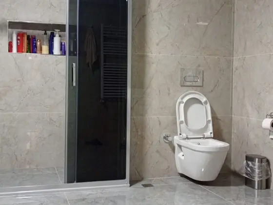 Siyah camlı duşakabin, seramik kaplı niş ve asma klozetli banyo